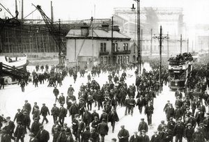 Fine del turno al cantiere navale Harland und Wolff, Belfast, Irlanda con il Titanic in costruzione sullo sfondo, 1910-11 da English Photographer