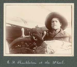 E H Shackleton in piedi accanto al timone della 