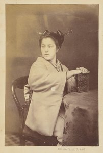 [Donna giapponese seduta con in mano un album di cartes-de-visite a un tavolo]. da Felice Beato
