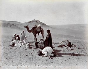 Cammellieri egiziani durante una pausa nel deserto. In primo piano, due membri del piccolo gruppo sembrano pregare