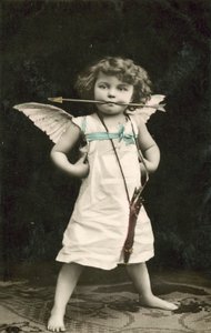 Bambino piccolo, vestito da Cupido, con una freccia in bocca da French Photographer