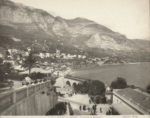 Vista panoramica di Montecarlo a Monaco. La scena mostra vari passanti; a sinistra vediamo un primo piano di una balaustra di marmo
