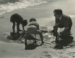 Tre bambini che giocano con la sabbia in spiaggia