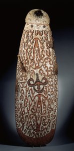 Scudo ovale Asmat, scolpito in rilievo con ornamenti a volute che incorporano figure altamente stilizzate, nappe intrecciate al bordo da Guinean New