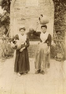 Due giovani donne che indossano abiti tradizionali e trasportano giare di terracotta vicino a un pozzo, Marche, Italia, 1910 ca. da Italian Photographer