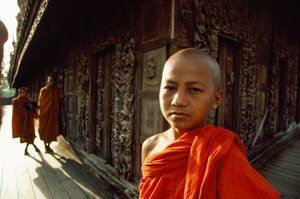 Un giovane novizio monaco davanti a pannelli di teak intagliati. Monastero di Shwenandaw, Mandalay, Birmania. da James L Stanfield