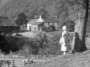 Una donna in piedi accanto a un albero, con le spalle alla telecamera, guarda verso la Yew Tree Farm da Joseph Hardman