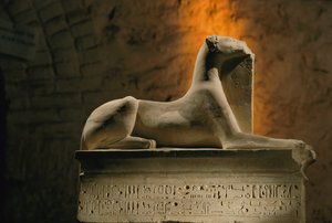 Statua in calcare del dio sciacallo Anubi accovacciato su una base a forma di sarcofago
