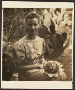 [Donna con mazzo di fiori seduta davanti a un cactus]