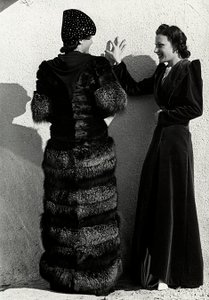 Due modelle presentano creazioni della casa di moda italiana "Dragoni". Una modella vista di spalle indossa un cappotto di volpe argentata. L