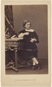 [Bambina non identificata, in piedi, con il gomito sopra un libro chiuso su un tavolo]. da Mayer and Pierson