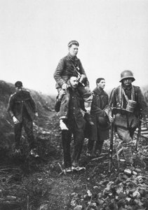Un soldato di fanteria tedesco con una gamba ferita viene portato fuori dalla battaglia da prigionieri di guerra inglesi