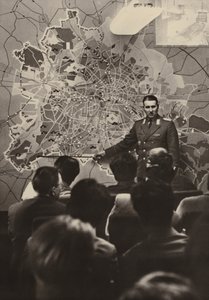 Un ufficiale delle Forze Armate del Popolo Nazionale spiega ai visitatori stranieri alla Porta di Brandeburgo la necessità del muro protettivo antifascista (foto in b/n) da Photographer German