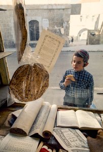 Ragazzo ebreo conservatore che mangia una torta guarda in una libreria religiosa da Ted Spiegel