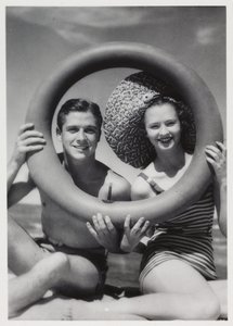 Uomo e donna che guardano attraverso un anello di gomma sulla spiaggia, c 1935