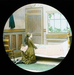 Una ragazza inginocchiata in preghiera accanto al suo letto, diapositiva della lanterna magica, c 1890