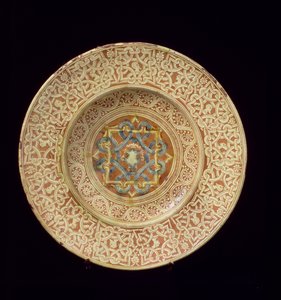 Piatto di maiolica decorato con un elaborato disegno a nodo ripetitivo che incornicia teste di profilo sul bordo e uno scudo nella placca centrale, italiano, fatto in Toscana