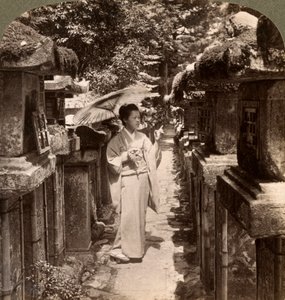 Una donna devota shintoista che conta le lanterne di pietra, Santuario Kasuga, Nara, Giappone da Underwood and Underwood