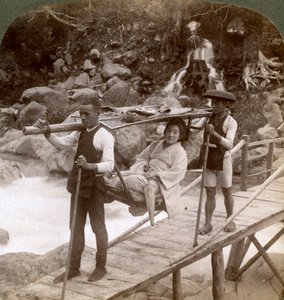 Donna giapponese in una sedia da montagna yamakago attraversa il torrente Daiya vicino a Nikko, Giappone