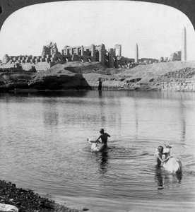 Guardando attraverso il Lago Sacro verso il grande tempio di Karnak, Tebe, Egitto da Underwood and Underwood