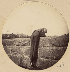 [Uomo con il cappello piegato su un muro di pietra] da Unknown artist