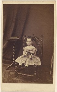 [Bambina non identificata che tiene in mano un cavallo di legno giocattolo, seduta]. da Unknown artist