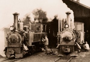 Due locomotive a vapore in manutenzione da parte di due operai da Unknown photographer