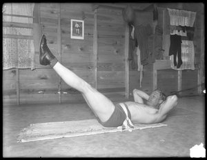 Pugile inglese William Thomas Wells (Bombardier Billy Wells), in posa con abbigliamento da allenamento facendo sollevamenti delle gambe, c.1911