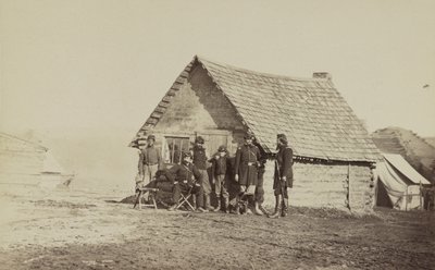 Un gruppo di soldati e due giovani, uno afroamericano, fuori dalle baracche di tronchi, 1861-65 da American Photographer