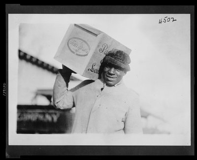 Uomo afroamericano che trasporta una cassa di whisky 