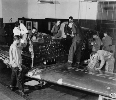 Soldati in addestramento lavorano su "Flying Patch," un aereo da combattimento Curtiss "Warhawk" senza motore o coda, con fori di proiettile simulati e toppe, c.1942 da American Photographer