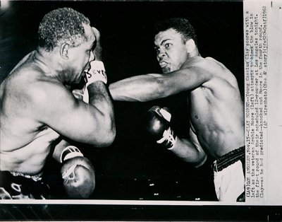 Il Giovane Cassius Clay colpisce con un sinistro il veterano Archie Moore nel primo round del combattimento a Los Angeles da American Photographer