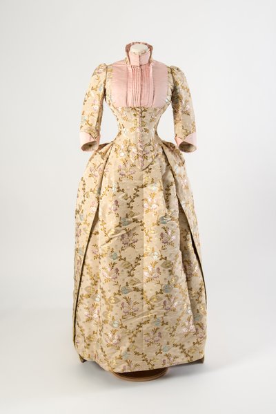 Abito di seta marrone chiaro tessuto con un disegno di fiori malva, blu e gialli e foglie verdi, pannello e polsini del corpetto in seta rosa chiaro da American School