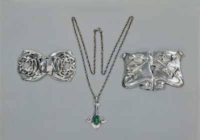 Gioielli in argento progettati per Liberty. Da sinistra a destra: Fermaglio per vita con design celtico intrecciato, 1904. Pendente e catena con crisoprasio cabochon. Fermaglio per vita con design a rilievo su martellato da Archibald Knox