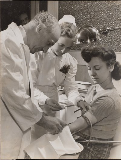 [Medico e infermiera inseriscono un ago nel braccio di una donna]. da Arnold Eagle