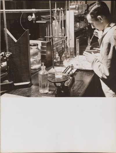 [Uomo in laboratorio usa entrambe le mani per mettere una grande pipetta in un becher]. da Arnold Eagle