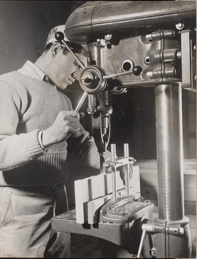 [Uomo usa una macchina per forare due blocchi di legno]. da Arnold Eagle