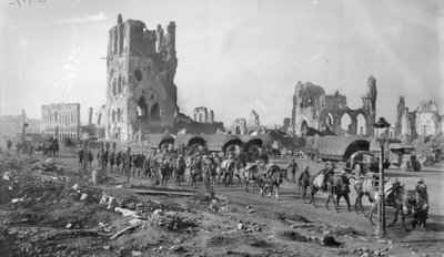Una sezione di mitragliatrici australiana non identificata con cavalli da soma che passa le rovine della Cloth Hall. Nota diversi camion a motore parcheggiati sullo sfondo, 19 ottobre 1917 da Australian Photographer