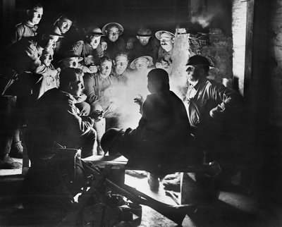 Membri della 1ª Batteria di Mortai da Trincea Leggera australiana, 1ª Divisione australiana che ascoltano le ultime notizie da uno dei loro compagni intorno a un fuoco in un alloggio scavato a Ypres, 28 ottobre 1917 da Australian Photographer