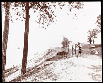 Vista di un ragazzo con un cannocchiale che guarda verso il fiume Hudson dal Riverside Park, New York da Byron Company