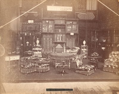 Esposizione di S. Howard & Sons -- Edificio principale, Collezione di mobili, inclusi sedie imbottite, tavoli, un camino, armadi e scaffali. Sulle pareti ci sono tappeti, e su tavoli e scaffali ci sono vasi da Centennial Photographic Co.