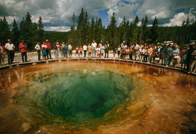 I visitatori del parco si radunano attorno a una piscina termale a forma di fiore blu-verde. Parco Nazionale di Yellowstone da Dean Conger