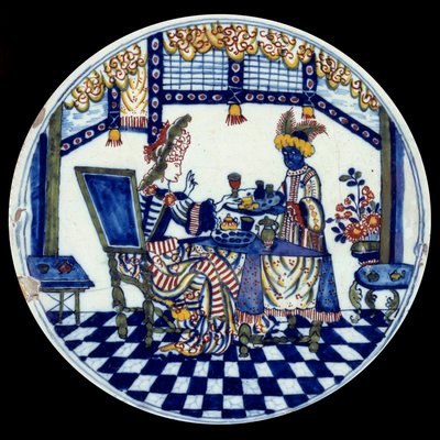 Piatto di porcellana di Delft che rappresenta una donna a un tavolo servita dal suo servo nero. 1705 da Dutch School