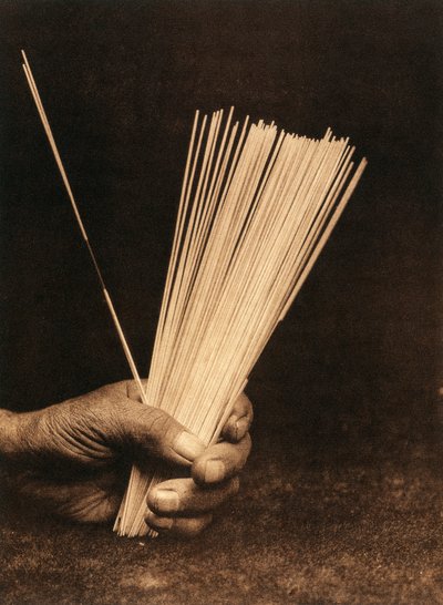 Primo piano della mano di un indiano della tribù o villaggio Hupa che tiene bastoncini di divinazione da Edward Sheriff Curtis