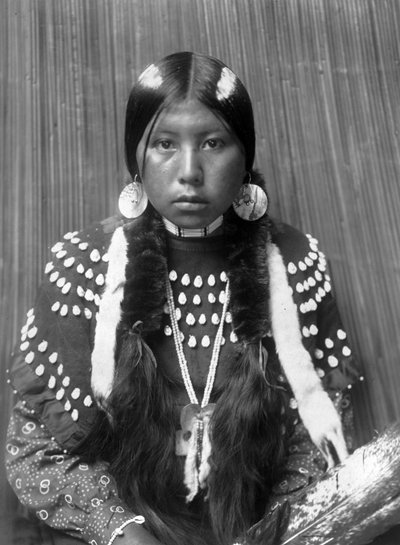 Donna indiana Kalispel, strisce bianche dipinte sui capelli, orecchini a disco di conchiglia, vestito a coperta decorato con denti di alce, c. 1910, foto Edward S. Curtis da Edward Sheriff Curtis
