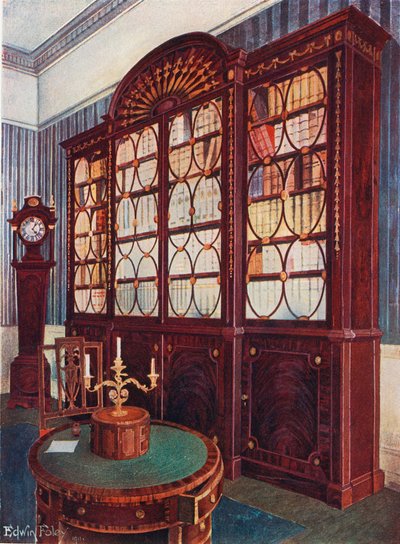 Libreria con frontale intarsiato in mogano. Tavolo centrale con piedistallo in mogano. Orologio alto in mogano da Edwin John Foley