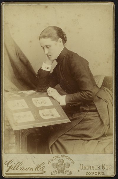 Figura di una donna seduta che ispeziona un album fotografico da English Photographer