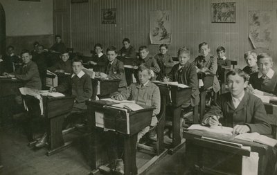 Alunni maschi seduti dietro i loro banchi durante una lezione a scuola da English Photographer