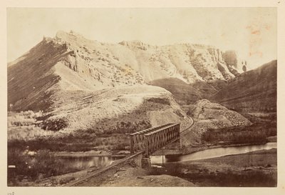 Vedute sulla ferrovia del Pacifico, binario ferroviario che attraversa un fiume su un ponte a travi, con montagne sullo sfondo da English Photographer
