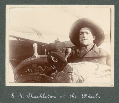 E H Shackleton in piedi accanto al timone della 